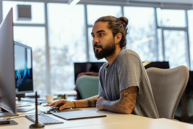 Woman with black curly hair wearing a backpack in a hallway holding and about to tap a phone